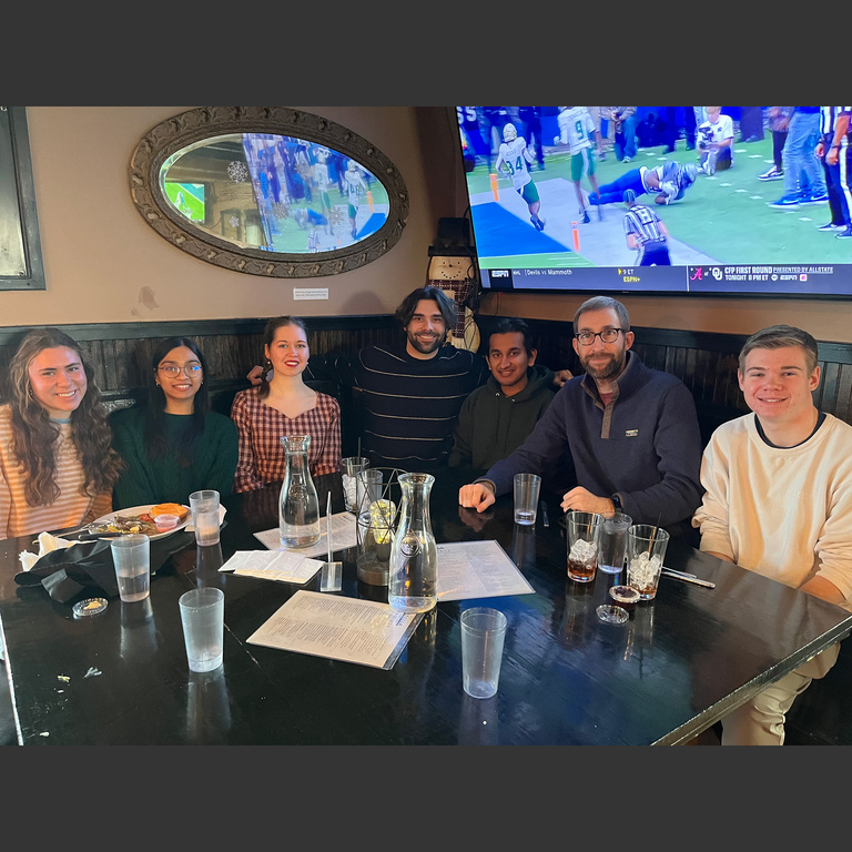 Lab members sitting at a restaurant table, smiling