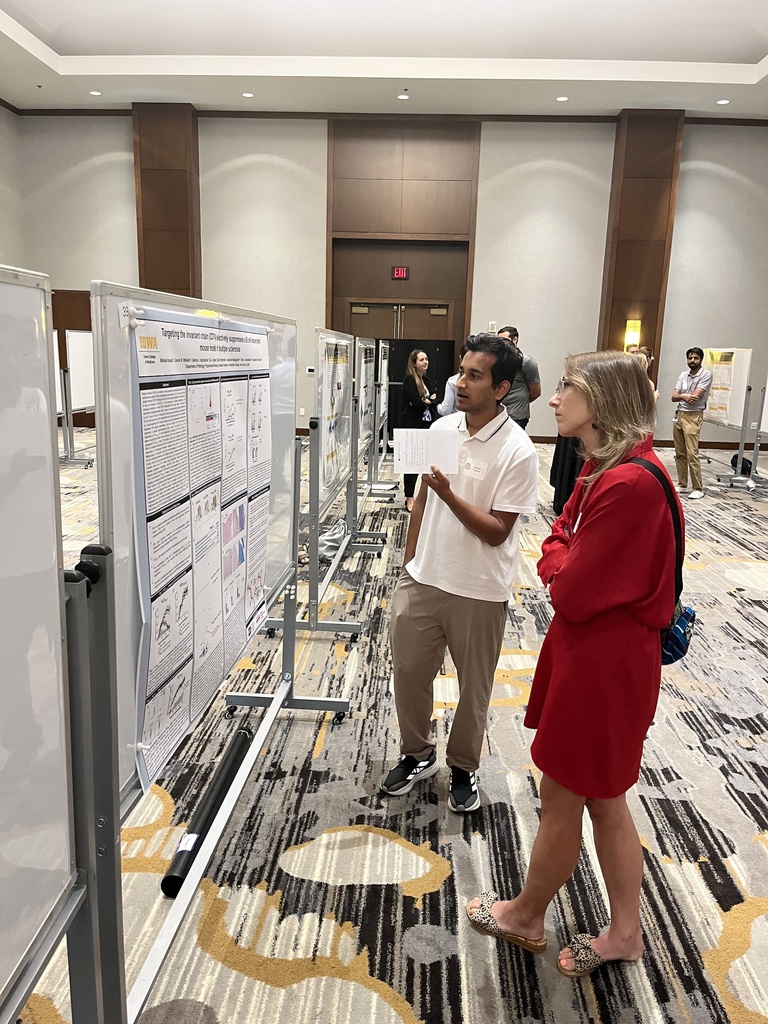 Two people in front of a research poster talking