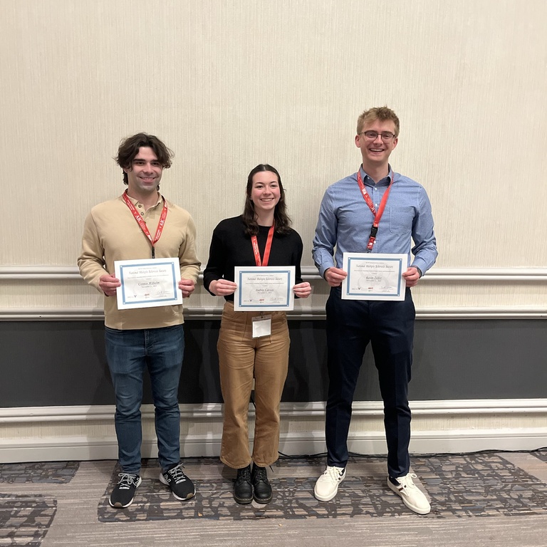 Three people holding awards, smiling