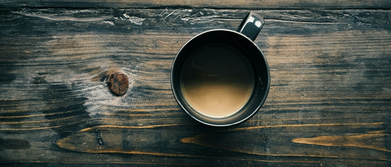 A cup of coffee sitting on a wooden surface